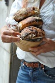 person holding 3 round loaves of home-made bread