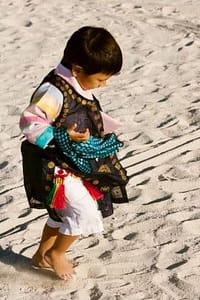 boy in trad Korean costume walking on sand