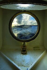 light above ship porthole, view of sea