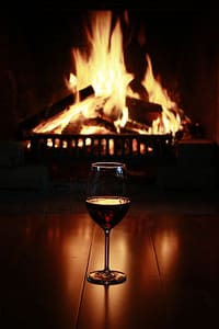 wineglass on wood floor in front of fire in a fireplace
