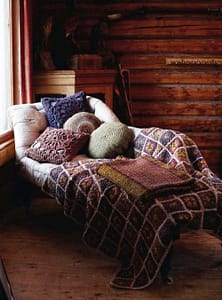 crocheted pillows and comforter on lounge by log wall