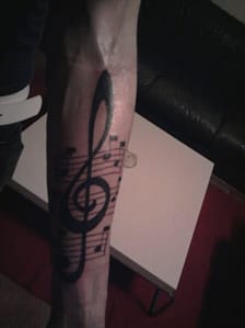 tattoo of musical clef and staves on forearm