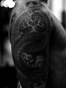 man's shoulder tat of looped snake photo by Thomas Hooper