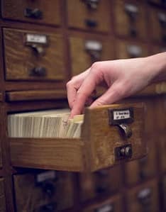 hand on library card catalog drawer, source unknown