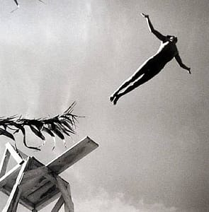 person mid-leap off high dive b/w photo