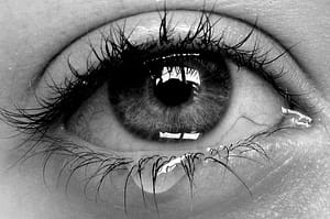 one eye with tear on lashes, b/w photo, closeup
