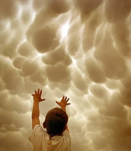 small boy reaching for clouds photo by Chris