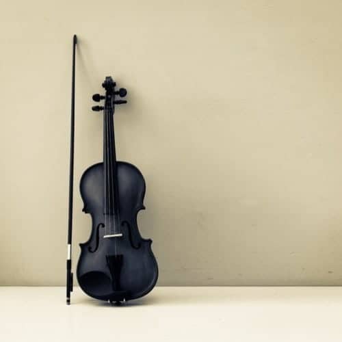 black violin and bow against tan wall